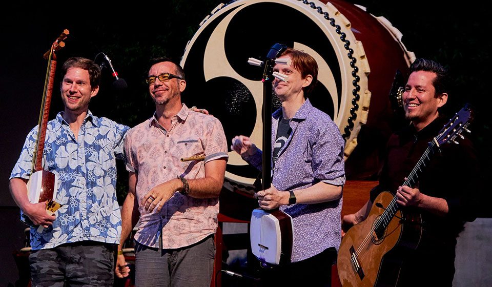 Kyle Abbott and fellow musicians on stage in front of a taiko drum